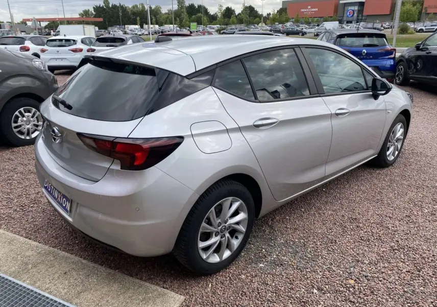 Opel Astra 2021 Sovereign Silver vue 3/4 arrière droit, jantes alliage 16'' gris argent et vitres surteintées.