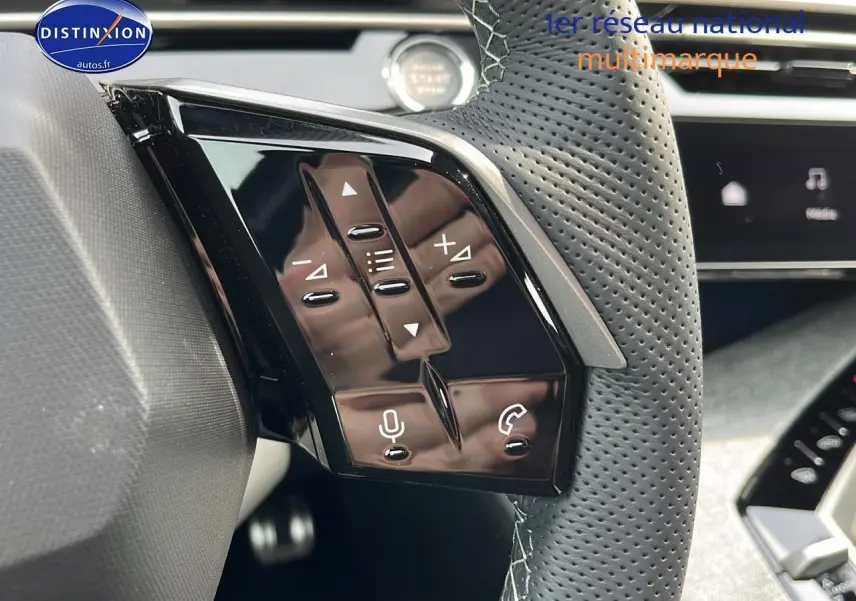 Gros plan sur les commandes au volant en cuir perforé du Peugeot 3008 gris hybride, avec boutons multifonctions et micro.