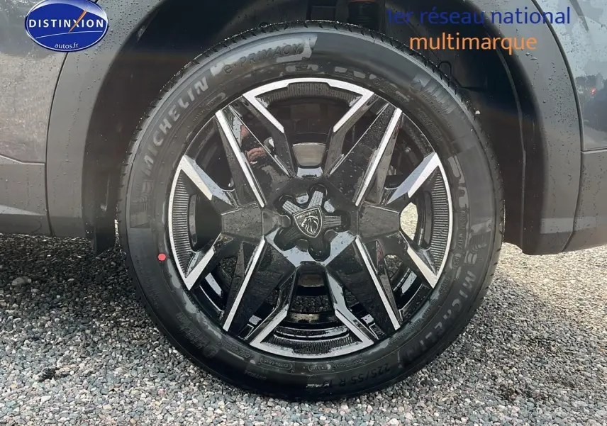 Gros plan sur la roue avant droite avec jante alu noire et grise du Peugeot 3008 gris 2025 hybride.
