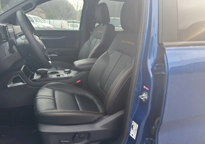 Vue intérieure côté conducteur du Ford Ranger Wildtrak bleu lightning, sièges cuir noirs avec surpiqûres orange et logo brodé.