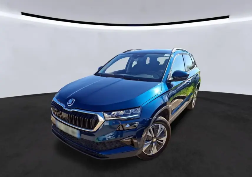 Vue 3/4 avant droite d'un Skoda Karoq bleu 2023 avec calandre chromée et jantes alu 17 pouces en intérieur.