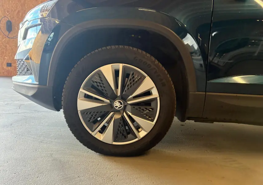 Gros plan sur la roue avant gauche et partie latérale d’un Skoda Karoq bleu avec jante alu 17 pouces design moderne.