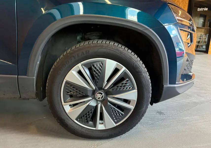 Gros plan sur la roue avant gauche du Skoda Karoq bleu 2023 avec jante alu 17 pouces et logo central distinctif.
