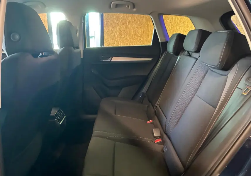 Vue intérieure côté droit des sièges arrière noirs du Skoda Karoq bleu 2023 avec appuie-têtes et ceintures visibles.