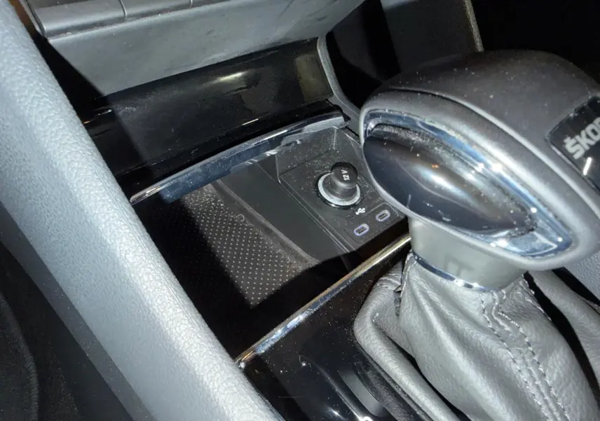 Gros plan sur le kit anticrevaison noir et bouteille de produit dans le coffre du Skoda Karoq bleu 2023.
