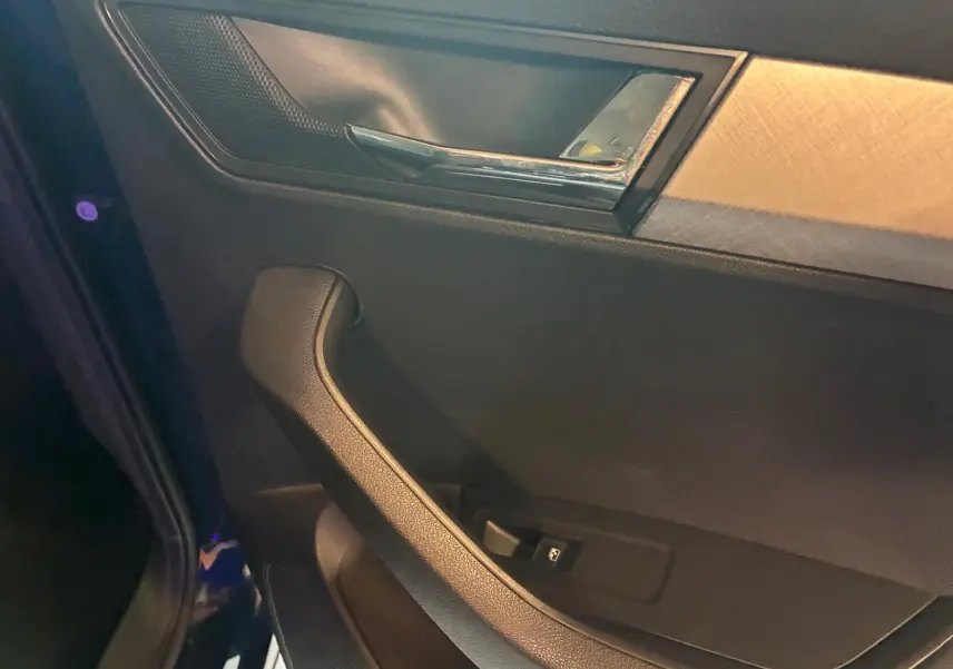 Détail de la porte intérieure côté gauche d'une Skoda Karoq bleu 2023 avec poignée noire et insert décoratif gris.