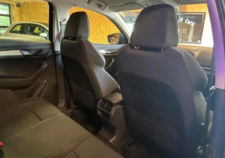 Vue intérieure arrière du Skoda Karoq bleu 2023, montrant les sièges noirs et les aérateurs centraux arrière.