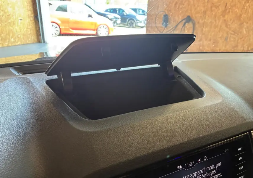 Vue intérieure du coffre à lunettes ouvert sur le tableau de bord noir d'une Skoda Karoq 2.0 TDI bleu 2023.