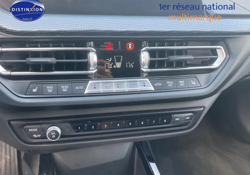Vue rapprochée de la console centrale de la BMW Série 1 gris foncé avec commandes clim et audio visibles.