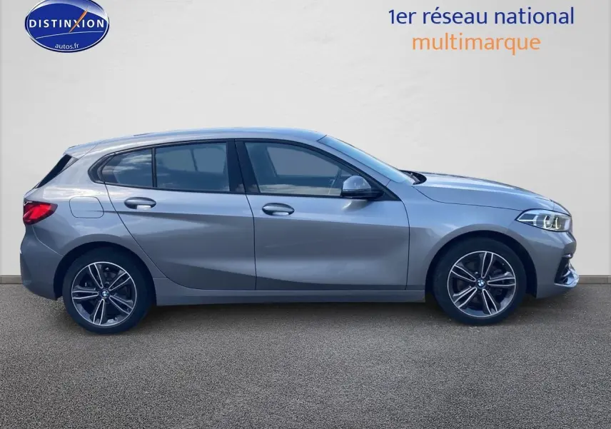 Profil côté gauche d'une BMW Série 1 gris foncé avec jantes alliage et phares LED visibles sur fond neutre.