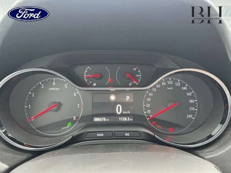 Tableau de bord de Ford avec compte-tours, vitesse et jauges, affichage numérique au centre, vue frontale rapprochée.