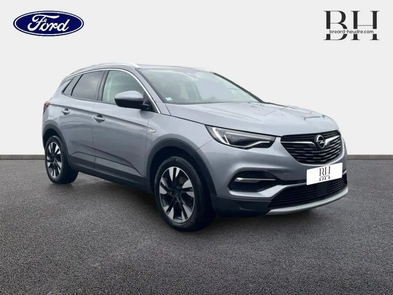 Opel Grandland X gris Quartz vu en 3/4 avant droit avec toit et rétroviseurs noirs sur fond neutre.