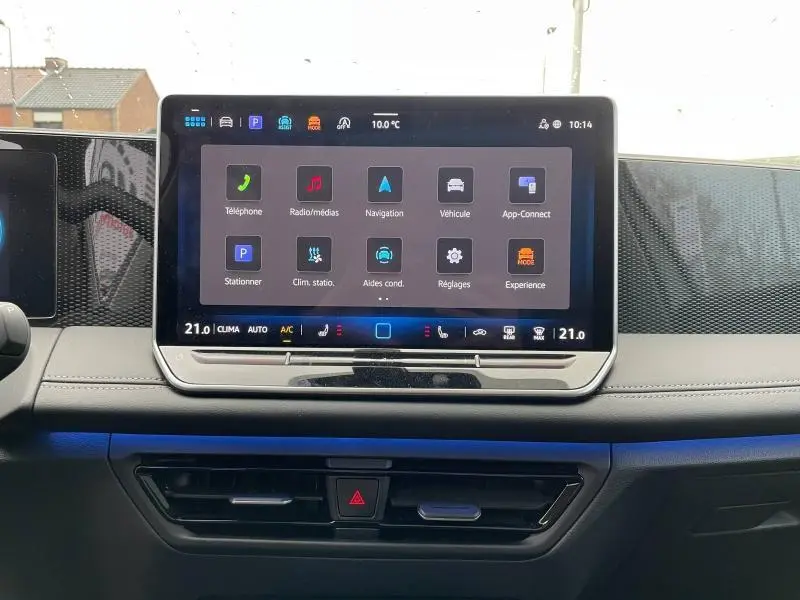 Écran tactile central du tableau de bord du Volkswagen Tiguan blanc, avec interface multimédia et commandes climatisation visibles.