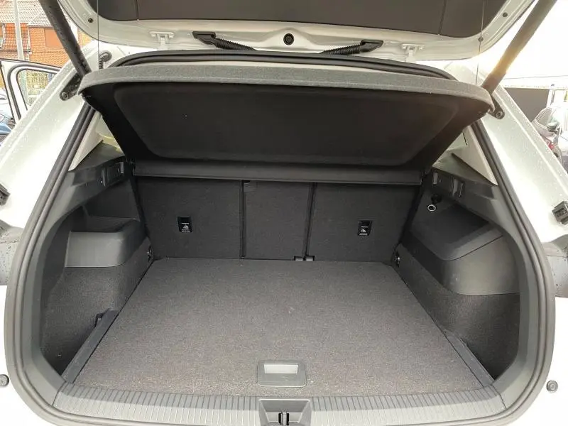 Coffre ouvert du Volkswagen Tiguan blanc pur 2025, vue arrière montrant un espace de chargement spacieux et tapis gris.