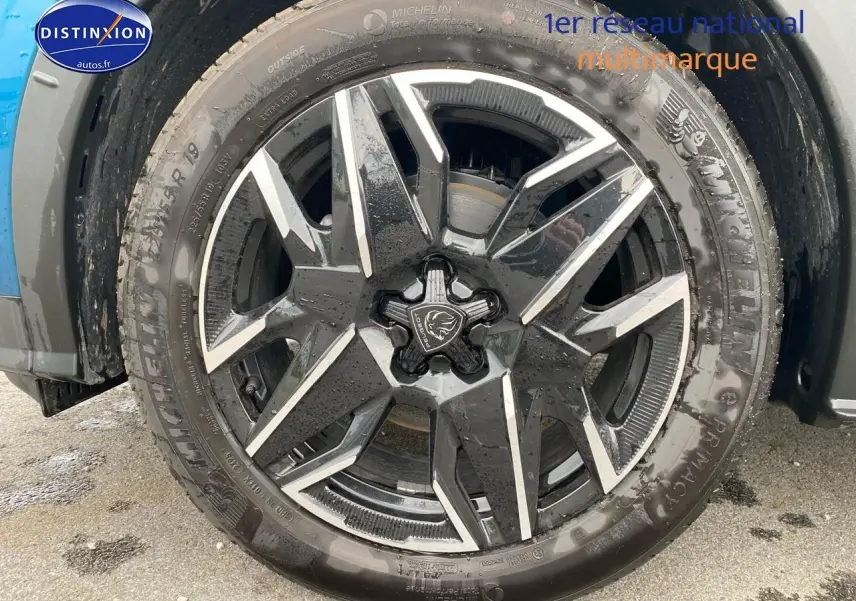 Gros plan sur la jante alu noire et argentée d’un Peugeot 3008 bleu, vue côté droit sous la roue avant.