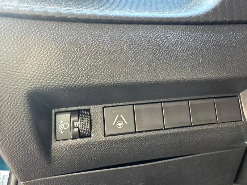 Gros plan sur les commandes de réglage des phares et d’aide au maintien de voie dans un Peugeot 2008 bleu 2025.