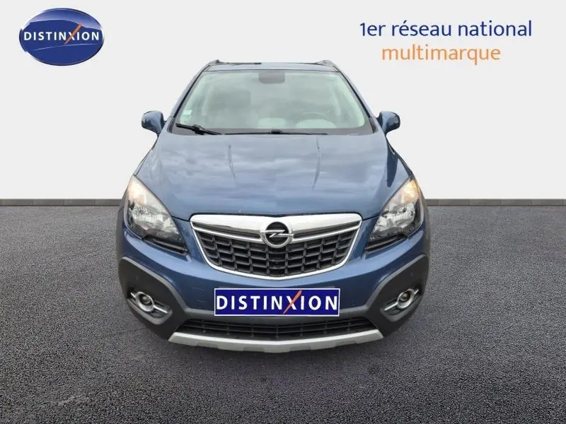 Vue avant d'un Opel Mokka bleu outremer avec calandre chromée et phares allumés sur fond neutre.