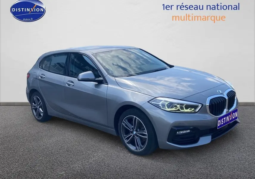 BMW Série 1 gris foncé vue 3/4 avant droit avec phares LED allumés et jantes alliage 17 pouces style 549