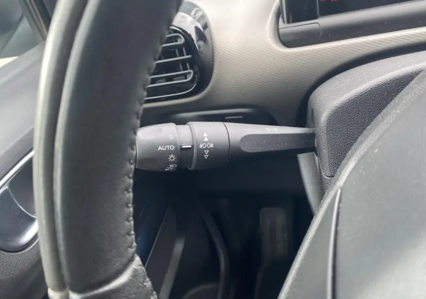 Gros plan sur la manette de commande d'éclairage à gauche du volant d'une Citroën C4 Cactus blanche.
