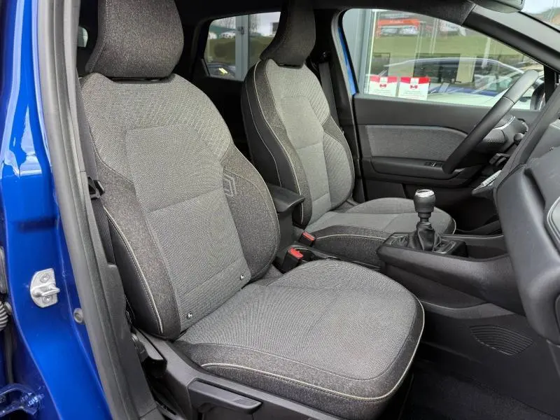 Vue intérieure côté gauche du Renault Captur 2025 Bleu Iron, montrant les sièges tissu gris et la boîte manuelle.