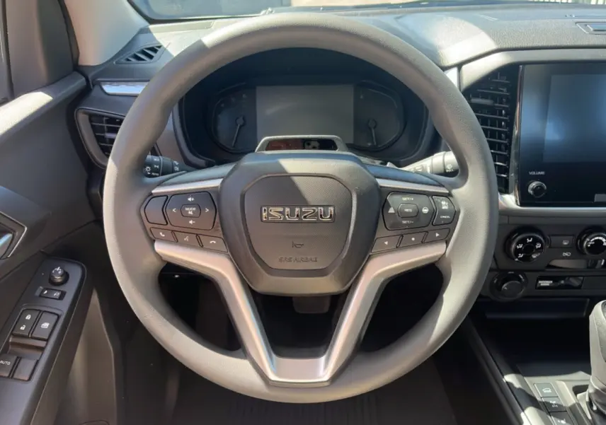 Vue rapprochée du volant multifonctions gris de l'Isuzu D-MAX 2026 avec tableau de bord et écran tactile.