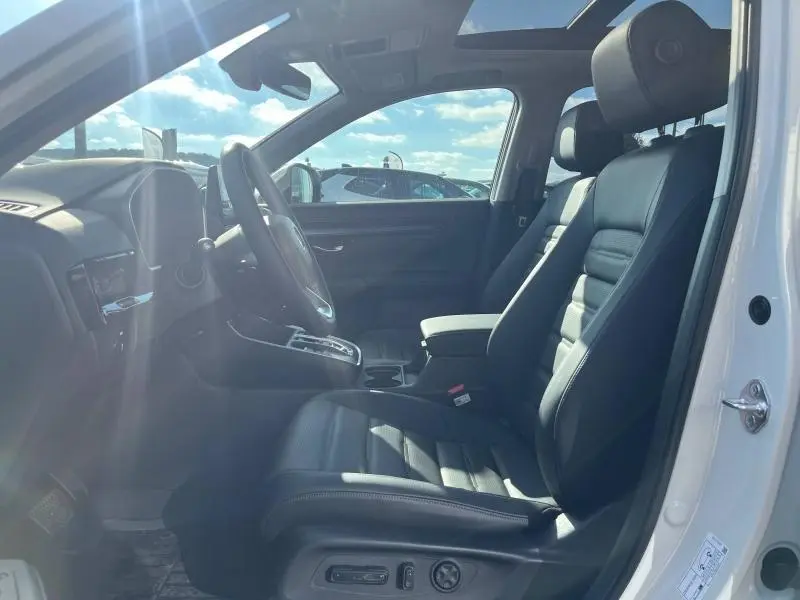 Vue intérieure côté conducteur du Honda CR-V 2024 avec sièges cuir noirs et toit panoramique en verre.