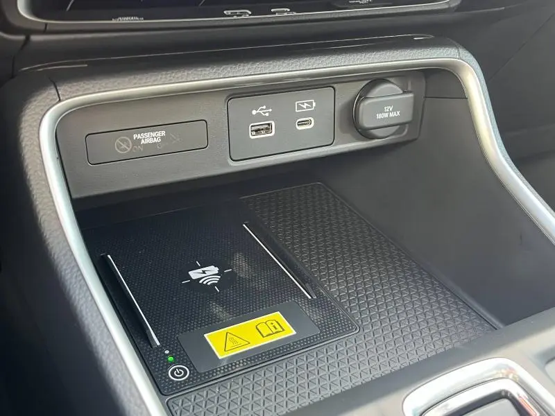 Vue rapprochée de la console centrale noire du Honda CR-V 2024 avec ports USB, prise 12V et chargeur sans fil.