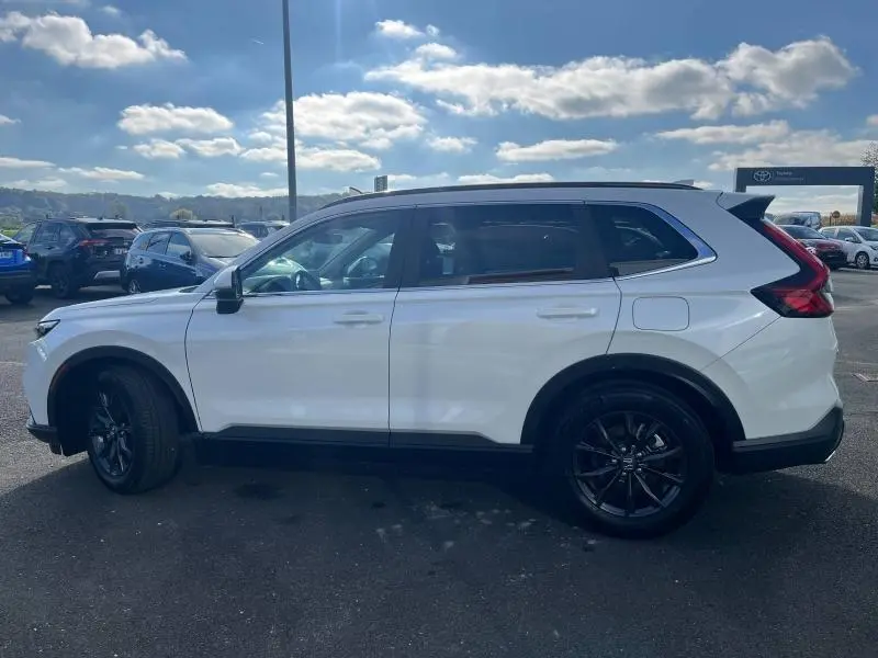 Profil côté gauche du Honda CR-V 2024 blanc Diamant Brillant Premium métallisé avec jantes noires et barres de toit.
