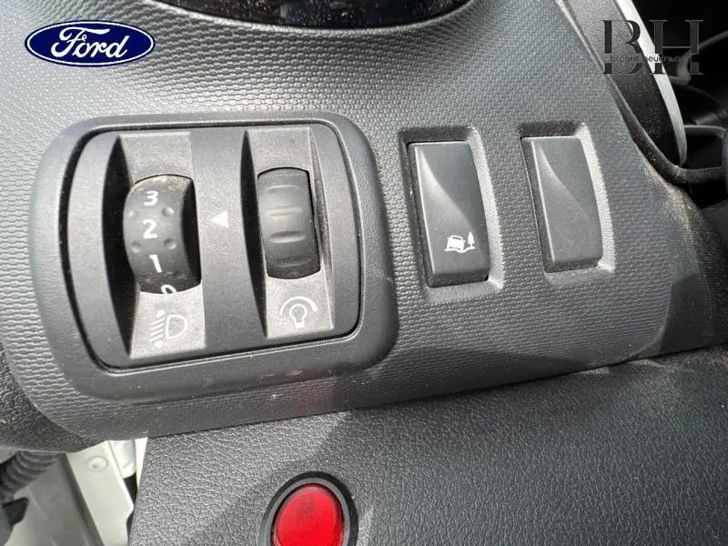 Gros plan sur les commandes d’éclairage et d’aide à la conduite du tableau de bord du Renault Trafic Fourgon blanc Glacier.