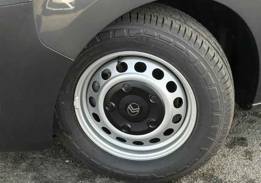 Gros plan sur la roue arrière droite d’un Citroën Jumpy gris titane avec jante acier et logo Citroën au centre.