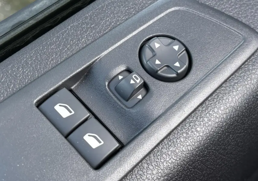 Gros plan sur les commandes de réglage des rétroviseurs et des vitres côté conducteur du Citroën Jumpy gris titane.