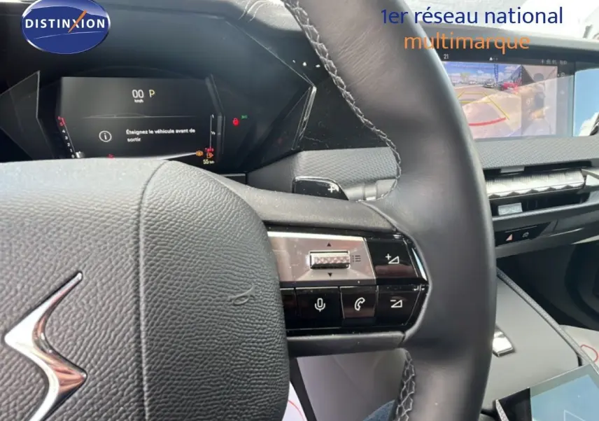 Vue rapprochée du volant cuir noir et du tableau de bord numérique du DS4 2024, avec écran multimédia et caméra de recul affichée.