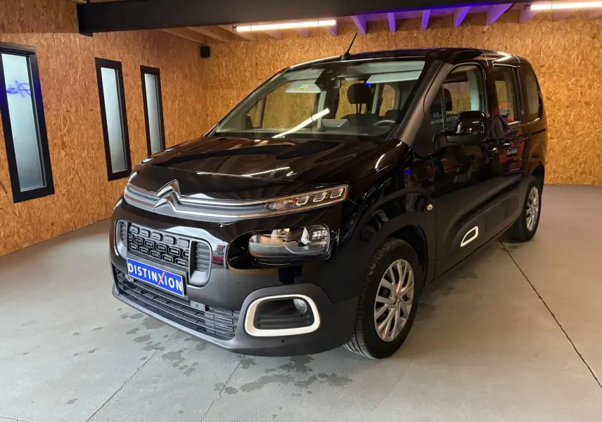 Vue 3/4 avant droit d'un Citroën Berlingo noir 2020, avec calandre distinctive et phares modernes dans un garage.