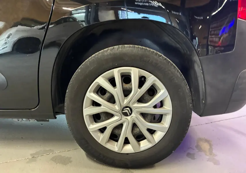 Gros plan sur la roue arrière droite noire d’un Citroën Berlingo 1.5 BlueHDi 100, jante argentée avec logo Citroën.