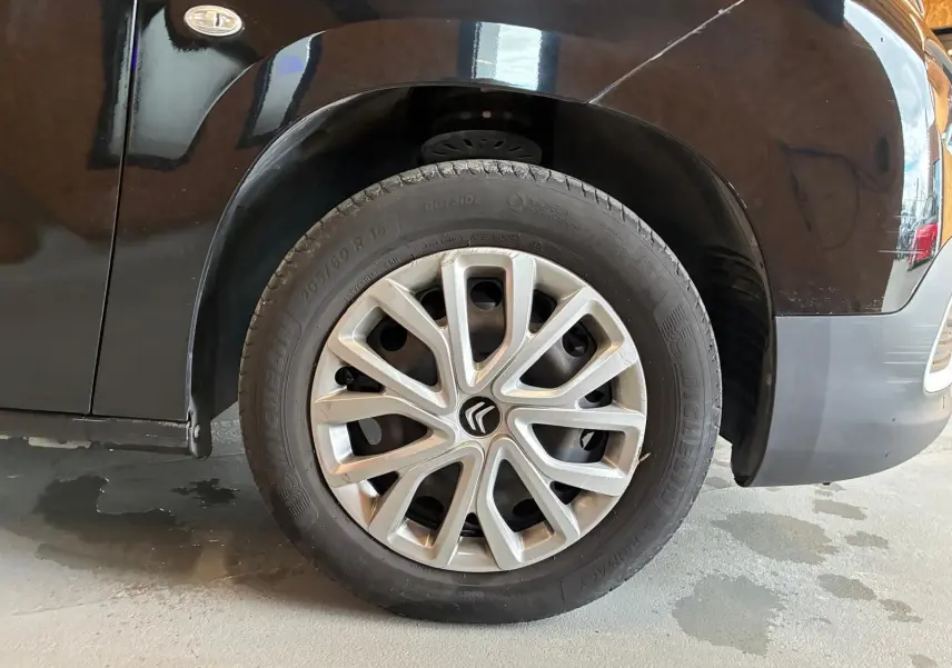 Gros plan sur la roue avant gauche d’un Citroën Berlingo noir 2020 avec jante en alliage et logo Citroën au centre.