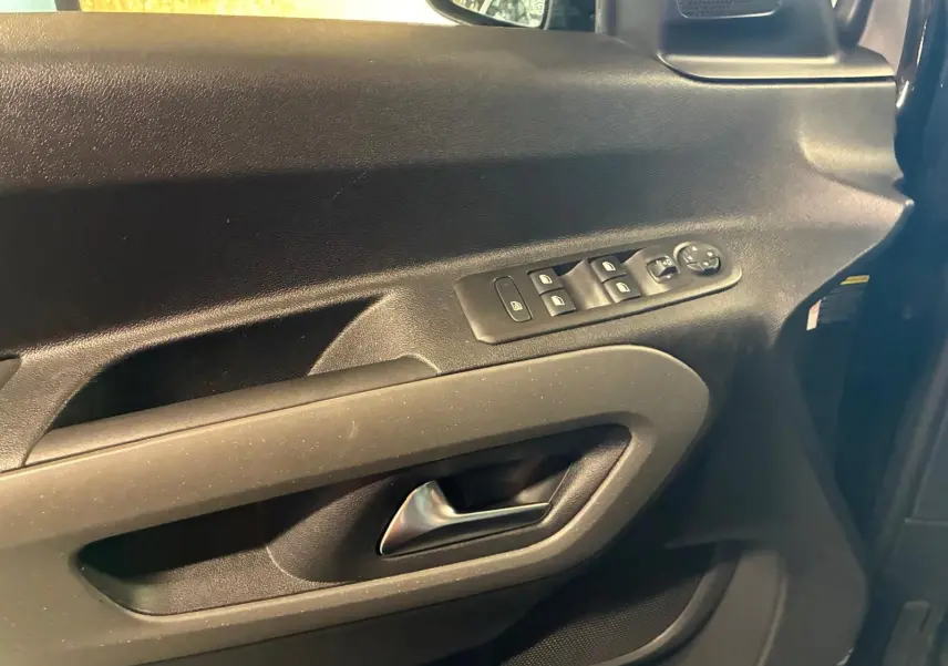 Vue rapprochée de la porte avant gauche noire du Citroën Berlingo 2020, avec commandes électriques et poignée intégrée.
