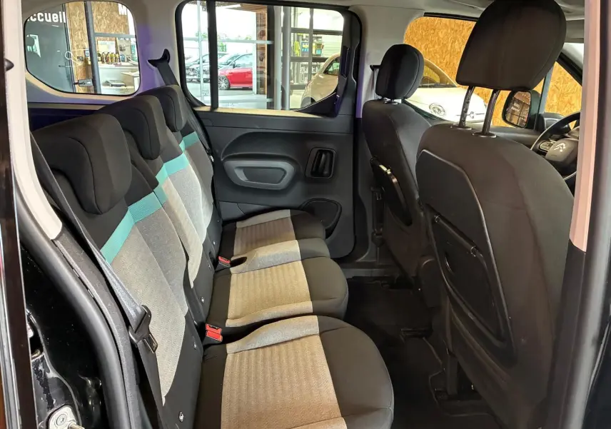 Vue intérieure côté gauche montrant la banquette arrière tissu gris et noir avec bande bleue du Citroën Berlingo noir 2020.
