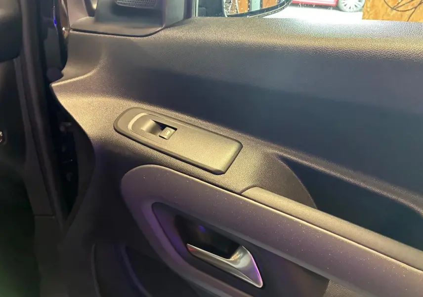 Détail de la porte intérieure côté gauche du Citroën Berlingo noir, avec commande de lève-vitre et poignée argentée.