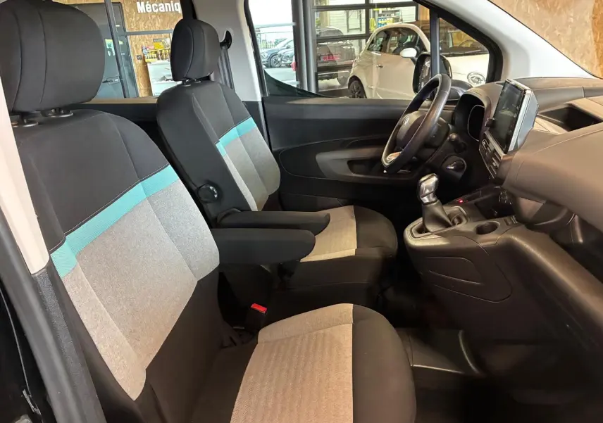 Vue intérieure côté conducteur du Citroën Berlingo noir 2020, montrant les sièges tissu gris et bleu et le tableau de bord avec écran tactile.