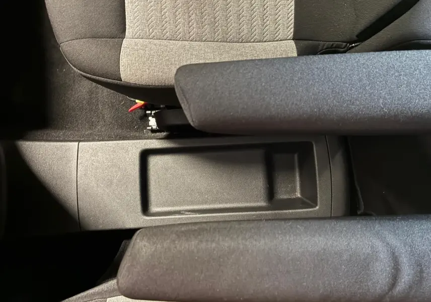 Vue plongeante sur le rangement central entre les sièges avant en tissu gris et noir du Citroën Berlingo noir 2020.