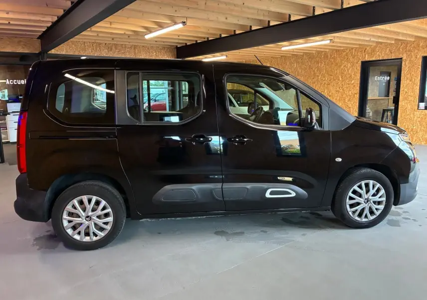 Profil côté gauche d'un Citroën Berlingo noir 2020 en intérieur, avec portes coulissantes et jantes alliage visibles.