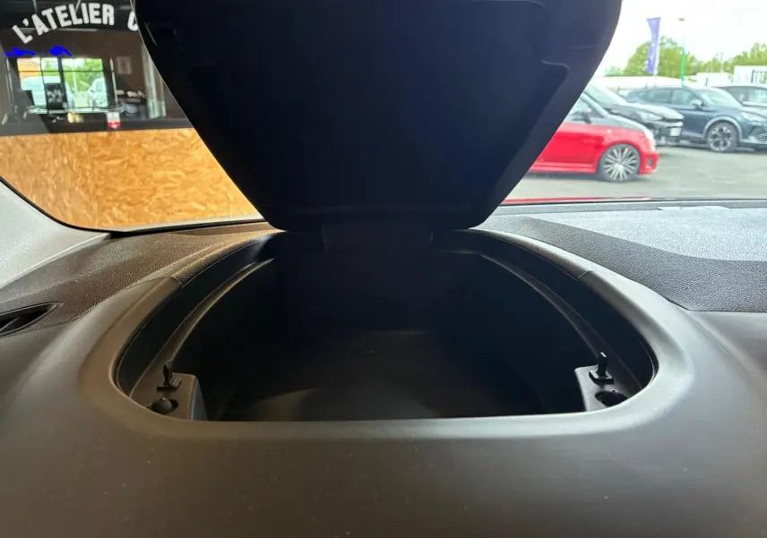 Vue rapprochée du coffre de rangement ouvert sur le tableau de bord du Citroën Berlingo noir, intérieur tissu noir visible.