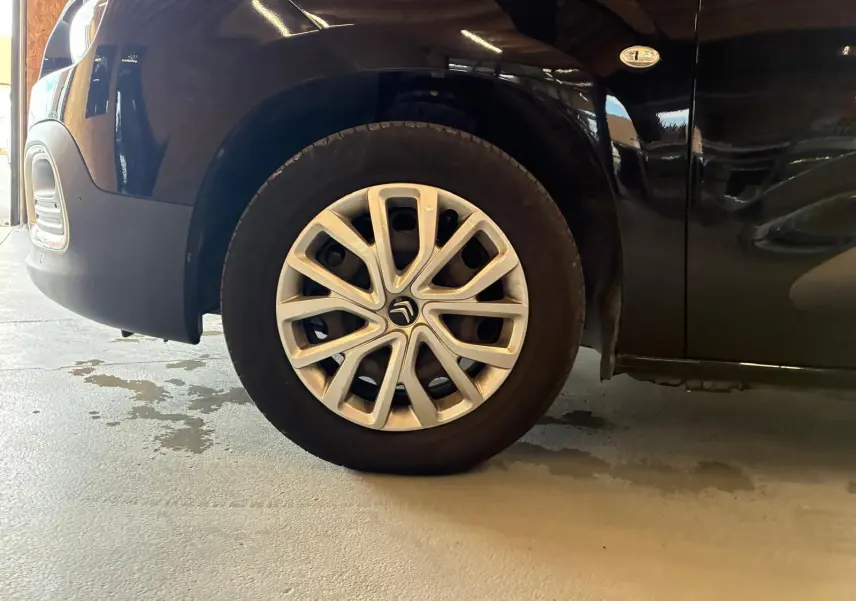 Gros plan sur la roue avant gauche d’un Citroën Berlingo noir 2020 avec jante alliage distinctive et badge 1.5 BlueHDi.
