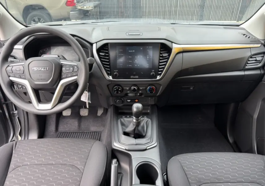 Vue intérieure avant du tableau de bord et volant multifonctions du pick-up Isuzu D-MAX avec sellerie tissu noire.
