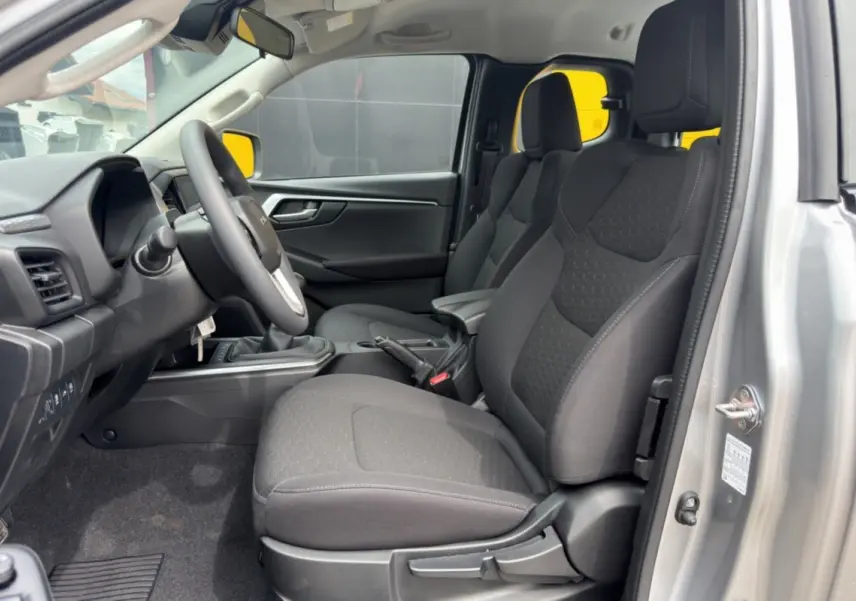 Vue intérieure côté conducteur de l'Isuzu D-MAX 2.2 TD 164 Space Evolution avec sièges tissu gris et accoudoir central.