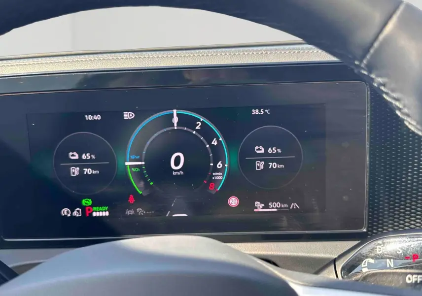 Vue rapprochée du tableau de bord numérique du Volkswagen Tiguan gris, affichant les indicateurs de vitesse et batterie.