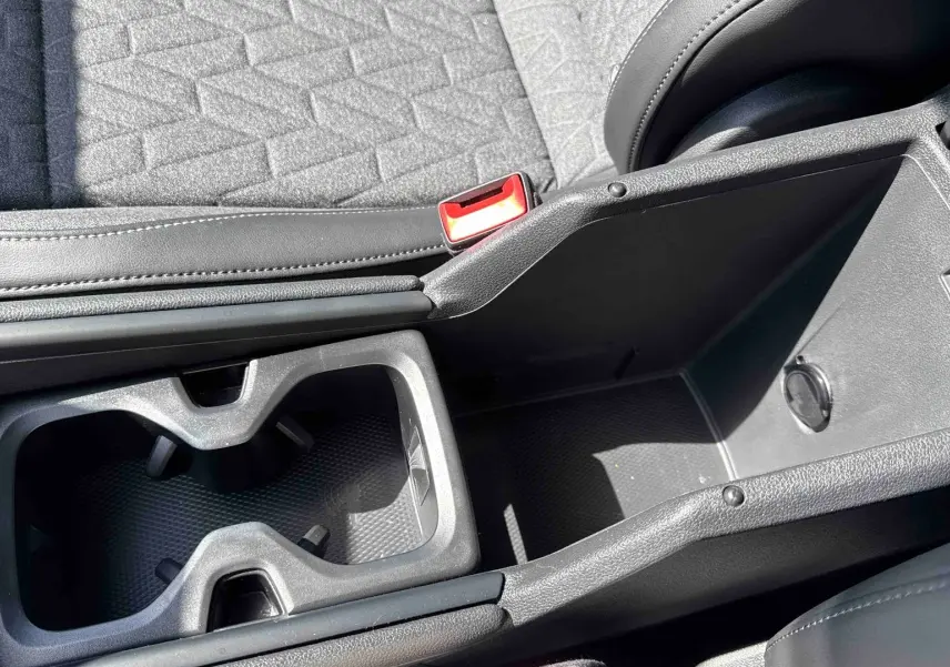 Gros plan sur la console centrale noire avec porte-gobelets et rangement du Volkswagen Tiguan gris 2025.