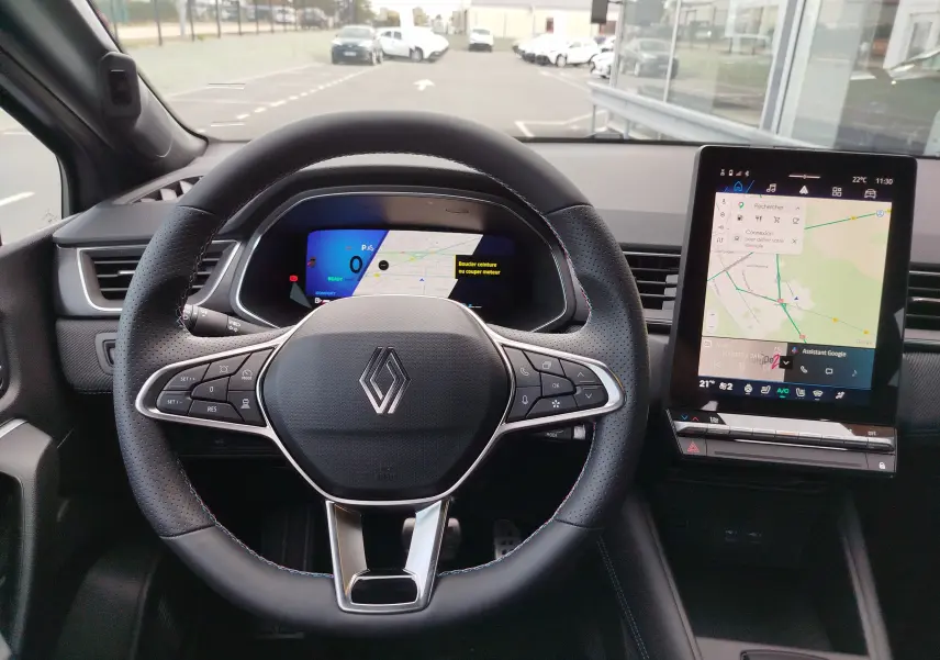 Vue intérieure centrée sur le volant noir perforé et l'écran tactile vertical du Renault Symbioz gris Cassiopée.