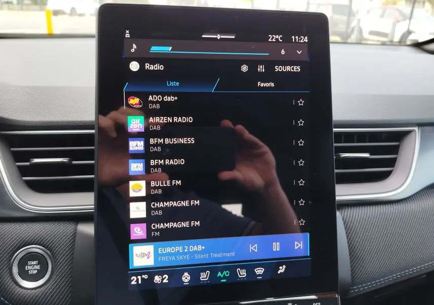Vue rapprochée de l’écran tactile central du Renault Symbioz gris cassiopée, affichant les stations radio DAB.