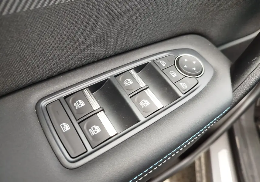 Gros plan sur les commandes de lève-vitres et réglage des rétroviseurs côté conducteur du Renault Symbioz gris cassiopée.